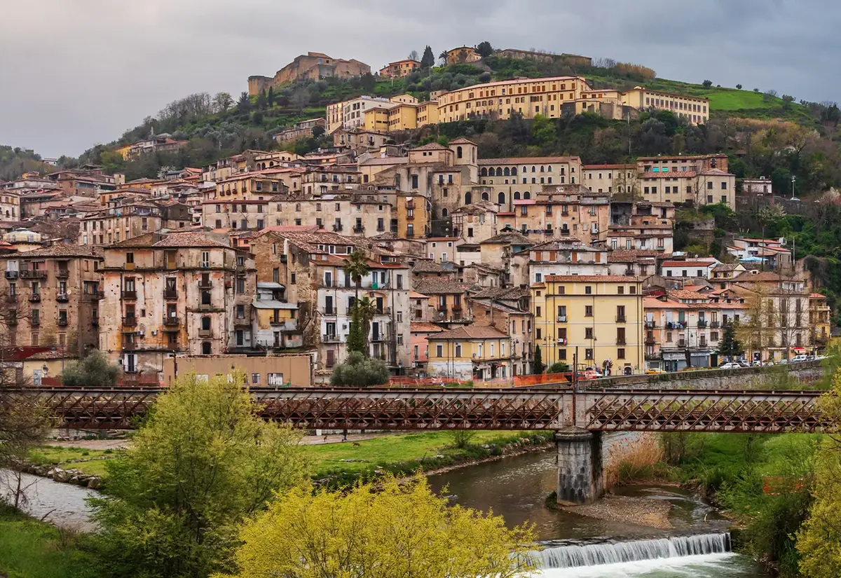 Il centro storico di Cosenza sul colle, con il Castello in cima e un ponte di ferro sul fiume